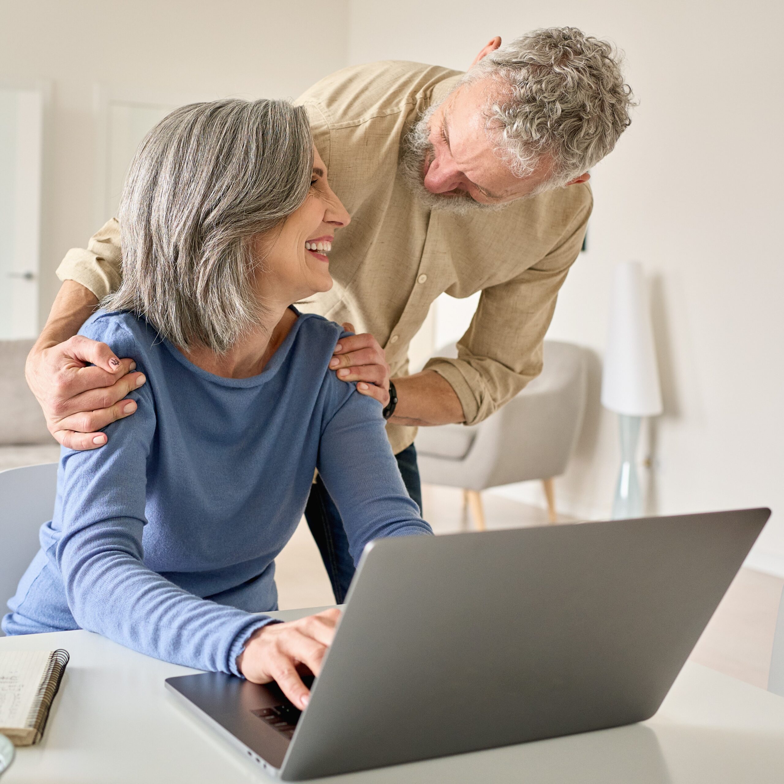 Happy mature senior couple laughing using laptop computer at home.